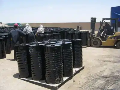 Workers loading Bitumen 15/25 drums onto pallets using forklift at ATDM facility.